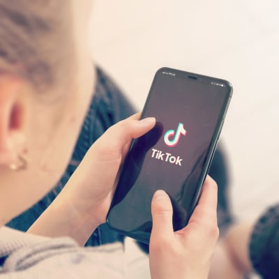 En person som håller i en telefon med Tiktoks logo på skärmen.