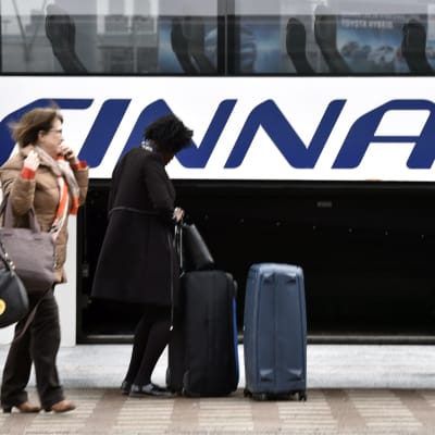 Passagerare får sitt bagage ur babageutrymmet på Finnairs flygbuss.
