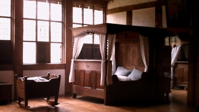 Parsäng och vagga i trä i ett sovrum.