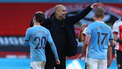 Pep Guardiola klappar två spelare på huvudet.