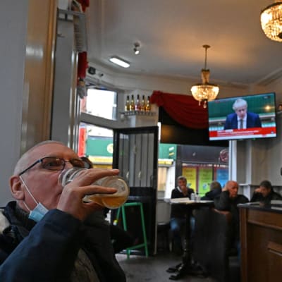 En man sitter på en pub i Liverpool och dricker ur ett stort ölglas.