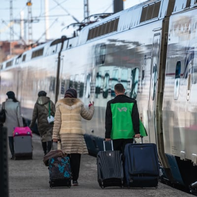 Viimeinen Allegro-juna lähti Pietariin Helsingin rautatieasemalta. VR:n työntekijä auttaa matkustajaa matkatavaroiden kanssa.