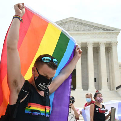 En man lyfter upp regnbågsflagga utanför USA:s högsta domstol den 15 juni 2020.