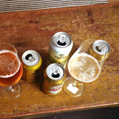 Ölglas och ölburkar på ett brunt bord.