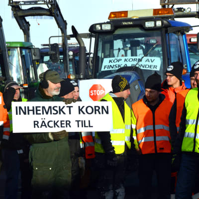 Bönder protesterar med plakat och traktorer i Vasa hamn.
