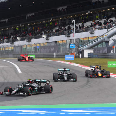 Vallteri Bottas svänger in i en kurva, följt av Lewis Hamilton och Max Verstappen.