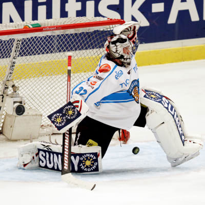 Blåvit finländsk ishockeymålvakt gör en räddning.
