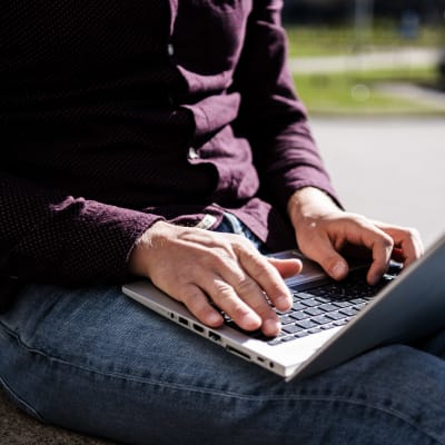 En person använder en laptop utomhus.