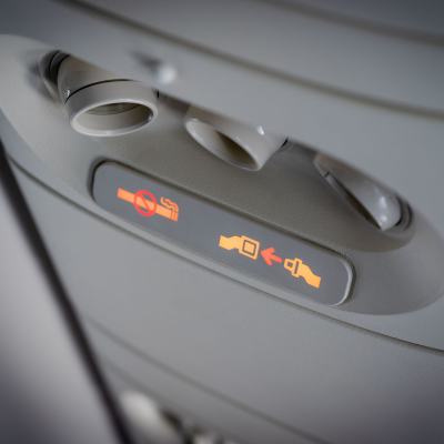 Två varningslampor lyser i en flygkabin: Fäst säkerhetsbältet, rök inte.
