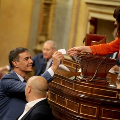 Spaniens premiärminister Pedro Sanches ler och ger en liten papperslapp till en kvinna.