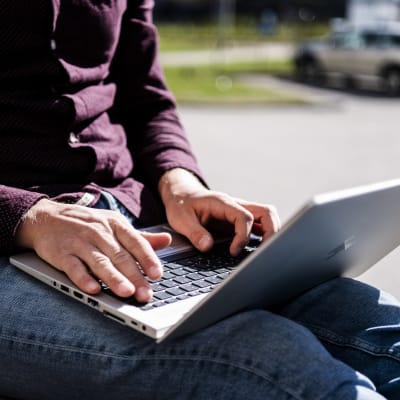 En person använder en laptop utomhus.