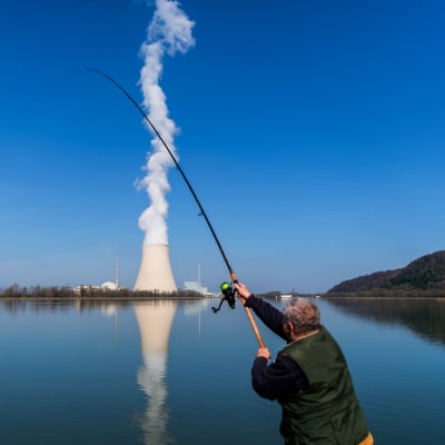 En man fiskar i den konstgjorda sjön vid kärnkraftverket Isar i södra Tyskland. I bakgrunden syns krafverkets kylningssystem.