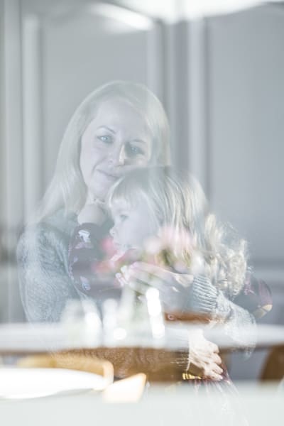 Reflektion av en mamma som håller sin dotter i famnen
