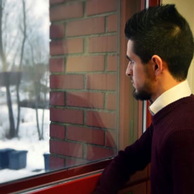 Saad Almosly tittar ut genom ett fönster.