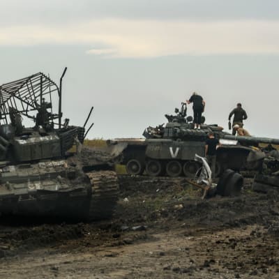 Ihmisiä kiipeilee tuhottujen venäläispanssarivaunujen päällä.