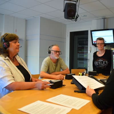 Sylva Heerman, Frank Holmlund och Kirsi Ala-Jaakkola står i Yle Västnylands radiostudio. Till höger syns programledaren Marica Hildén.