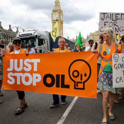 Joukko mielenosoittajia kantaa kylttejä, joissa lukee "just stop oil" sekä "our government the criminal".