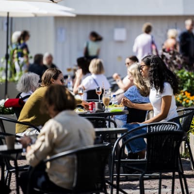 Människor äter och dricker på terrassen på Senatstorget i Helsingfors i juli 2020.