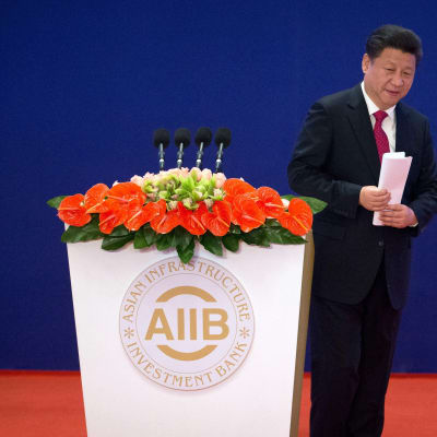 Kinas president Xi Jinping på väg från ett talarpodium med texten Asian Infrastructure Investment Bank.