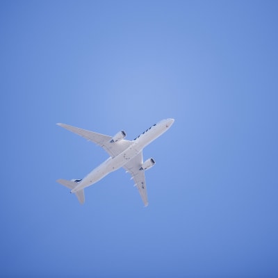 Ett vitt flygplan fotograferat nerifrån mot en bakgrund av blå himmel. Det är ett Finnairplan som flyger över Böle i Helsingfors i juni 2020.