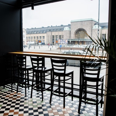Fyra tomma restaurangstolar framför ett fönster intill Helsingfors järnvägsstation.