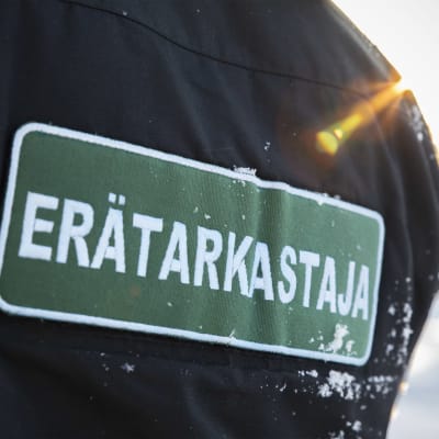 Erätarkastaja-merkki takin selkämyksessä.