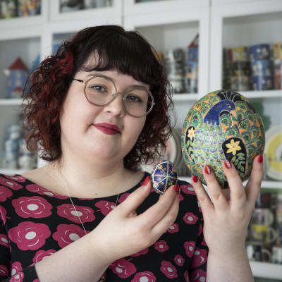 Hanna Lintu esittelee koristeelliseksi maalattua strutsinmunaa ja kananmunaa.