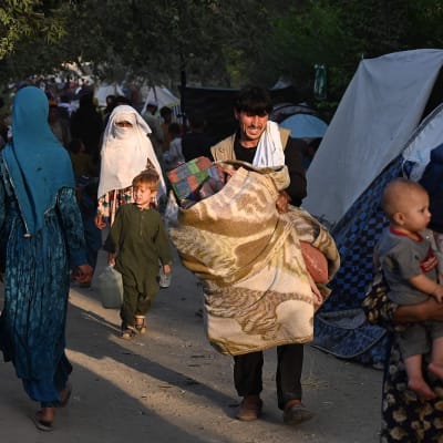 Ihmisiä, jotka ovat joutuneet pakenemaan kodeistaan, kävelemässä väliaikaisten telttamajoitusten ohi.