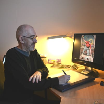 Äldre man sitter framför dator. Han håller i en penna och ritar på en ritplatta. På datorskärmen synns en frägglad teckning av en människa.
