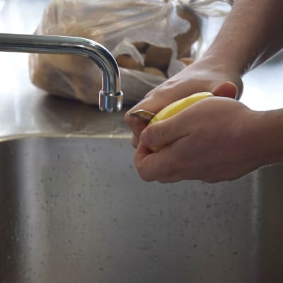 händer över lavoar med potatis och kniv