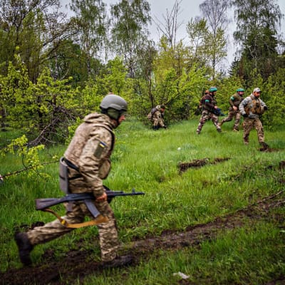 Ukrainan sotilaat juoksevat suojaan pommitusten aikana lähellä Bahmutia 30. huhtikuuta 2023.