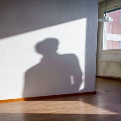 Tyhjä myytävänä oleva asunto, seinällä ihmisen varjo.
