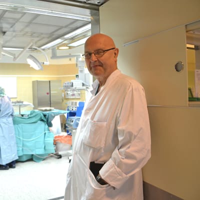 Hjärtkirurg Kalervo Werkkala står vid ingången till en operationssal på Vasa centralsjukhus.