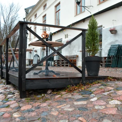 Café Fannys träterrass byggt på sluttande mark med runda stenar