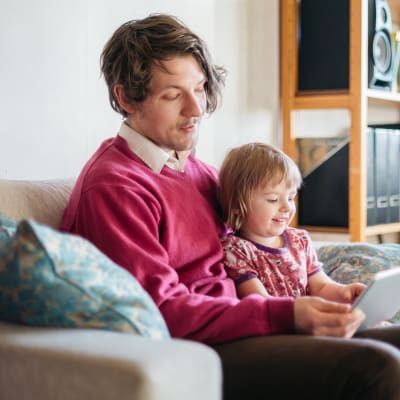 En man och ett barn tittar tillsammans på ett program via en datorplatta.