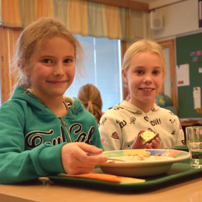 Eleverna Liv Svartsjö och Clara Åbrendt i Gerby skola äter lunch vid sina pulpeter.