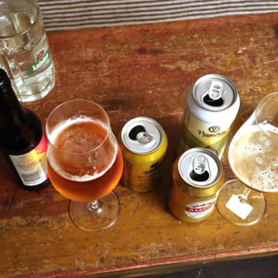 Ölglas och ölburkar på ett brunt bord.
