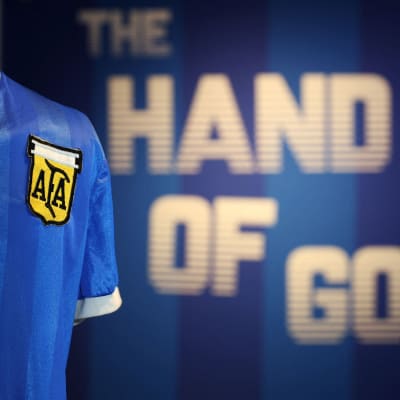 Diego Maradonas speltröja med texten Hand of God i bakgrunden.