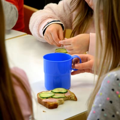 Barn äter en smörgås på ett daghem.