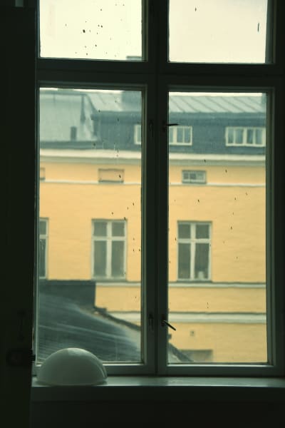 Smutsigt fönster inifrån Lappvikens sjukhus genom vilket man ser en gul fasad på andra sidan av en innergård.