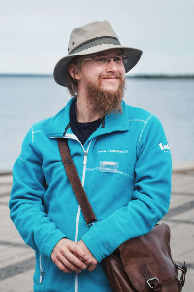 Toni Junes står framför inre hamnen i Kemi med en hatt på huvudet, leende bakom sitt tomteskägg.