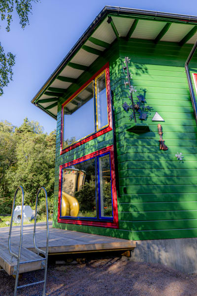 Ett knallgrönt sexkantigt hus med konstverk på fasaden. 
