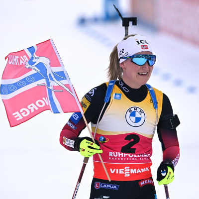 Marte Olsbu Røiseland med norska flaggan i högsta hugg efter en seger i världscupen i skidskytte.
