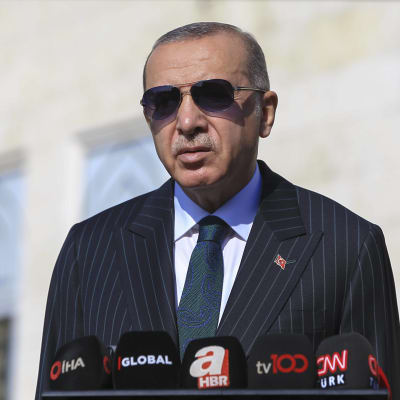 Turkiets president Recep Tayyip Erdogan i solglasögon vid ett talarpodium.