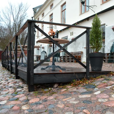 Café Fannys träterrass byggt på sluttande mark med runda stenar