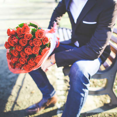 Man med röda rosor på en bänk.