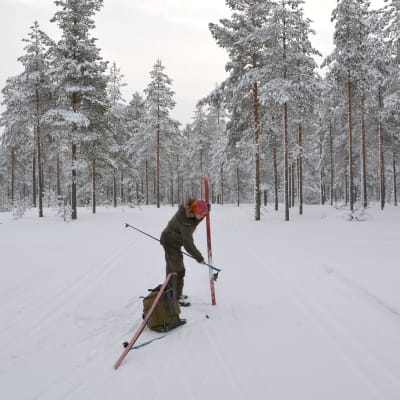Patrik Berghäll putsar bort snö från skidorna.