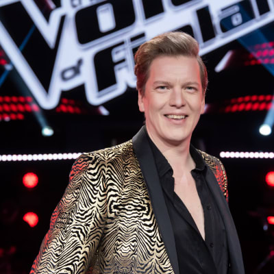 Heikki Pöyhiä hymyilee promokuvassa Voice of Finlandin lavasteissa.