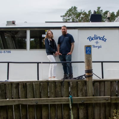 Ett par som står framför en båt.
