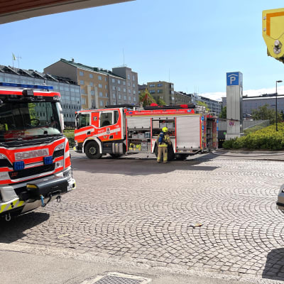 Kolme paloautoa Lahden toriparkin edustalla. Yksi palomies hommailee paloutolla.